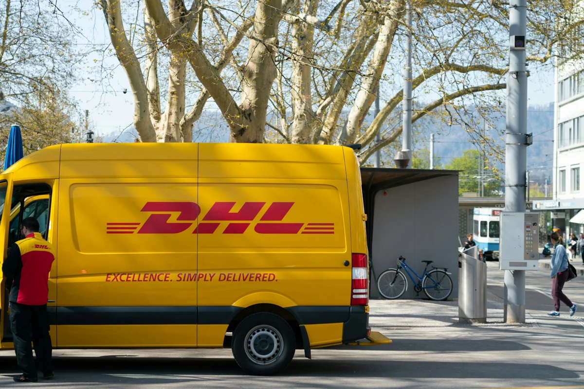 DHL courier beside a yellow DHL van